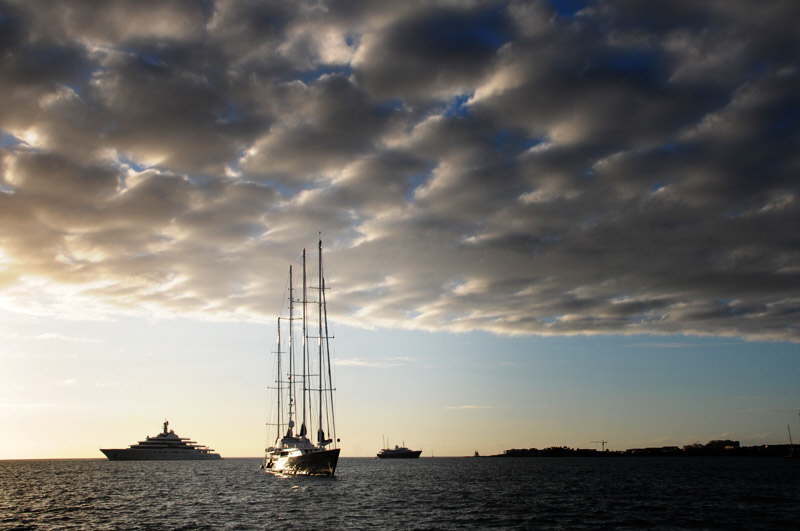 Det firmastede sejlskib kan sejles af n mand. I baggrunden verdens strste privatejede motoryacht. Ejer: Russiske Abramovich.